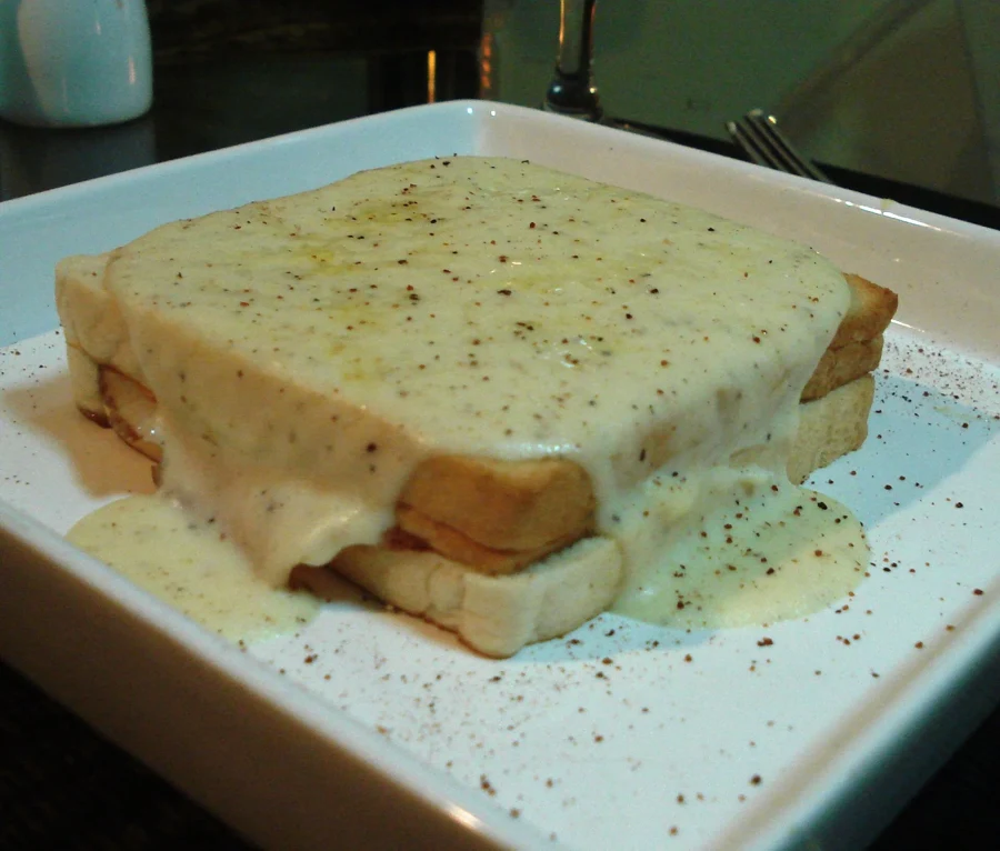Croque-monsieur au four nappé de béchamel gratinée sur une assiette