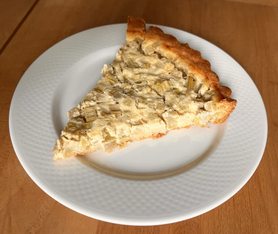 Part de tarte à la rhubarbe dorée posée sur une assiette blanche