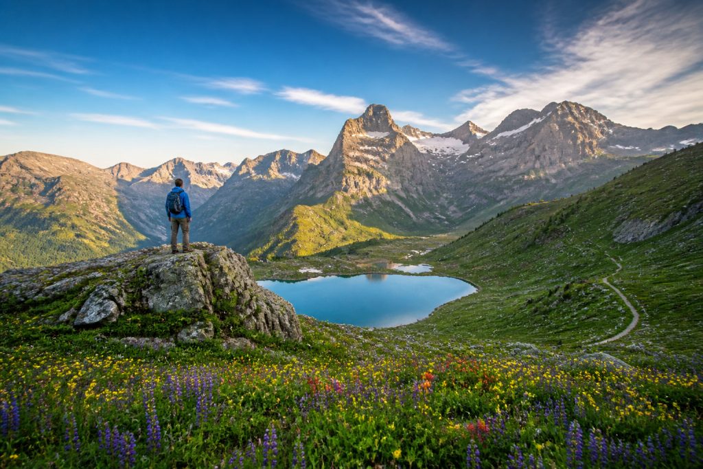 Randonneur contemplant un lac alpin