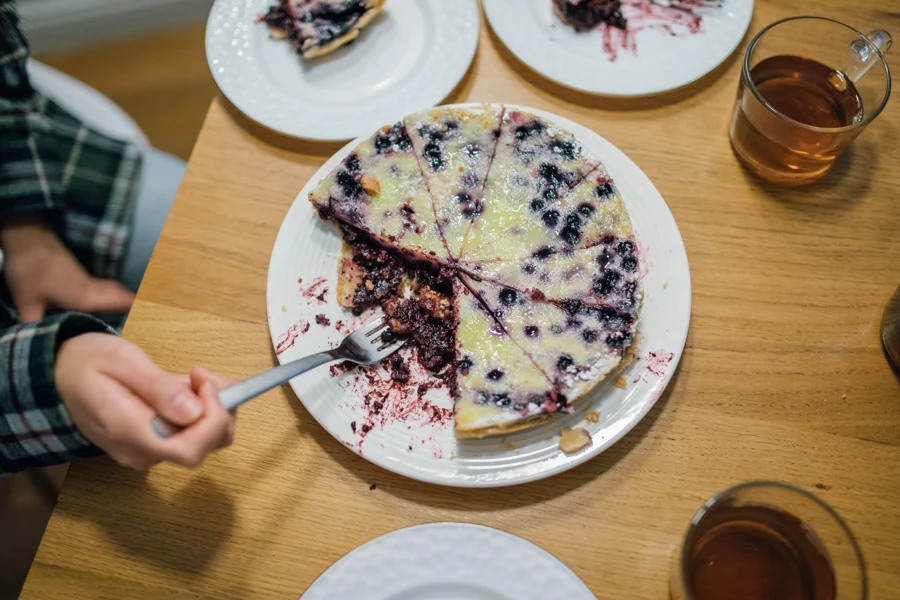 Tarte aux myrtilles à la crème découpée, une part servie à la fourchette