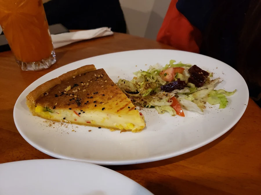 Part de quiche au fromage dans une assiette, avec une salade verte