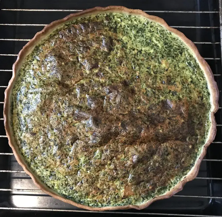 Quiche aux épinards cuite, appareil gonflé et bords dorés